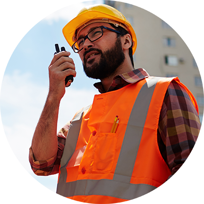 man in construction hat talking into a 2 way radio